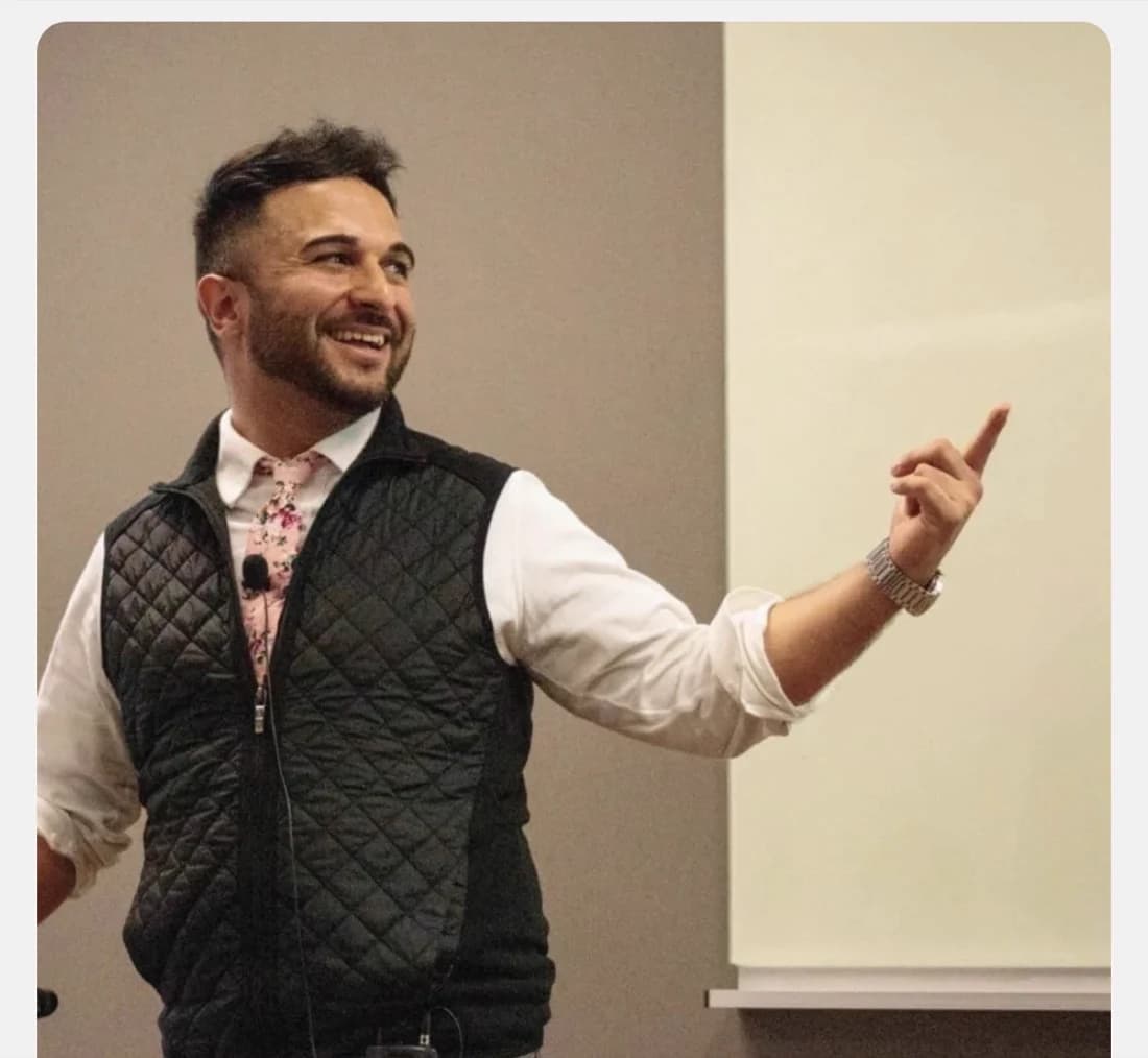 Leo Morejon speaking on stage, pointing toward the audience
